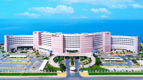 a large pink building with a courtyard in front of it at Grand Millennium Gizan in Jazan
