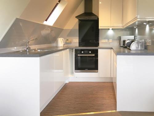 a kitchen with white cabinets and a black oven at Pine Lodge - Uk7049 in Glenurguhart