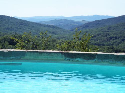 a pool of blue water with mountains in the background at Peaceful Eco House in the Tuscan Hills in Casole dʼElsa