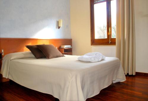 1 dormitorio con 1 cama blanca grande y ventana en Fonda Barris, en Joanetes