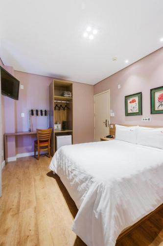 a bedroom with a large white bed and a kitchen at Araçatuba Plaza Hotel in Araçatuba