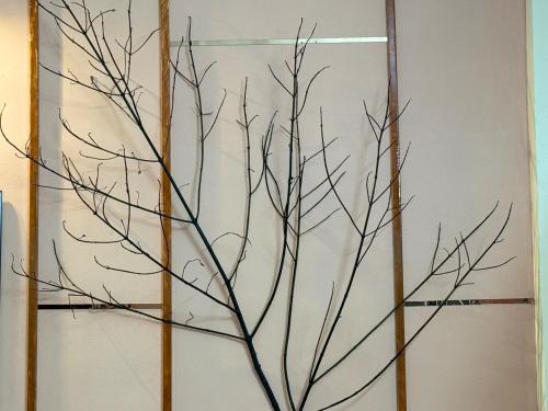 a painting of a tree branch on a wall at TriNest Garden Villa in Nagpur