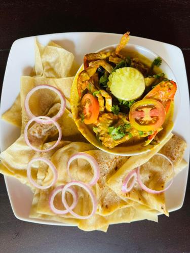 a plate of food with a taco and chips at Traget safari home stay in Udawalawe