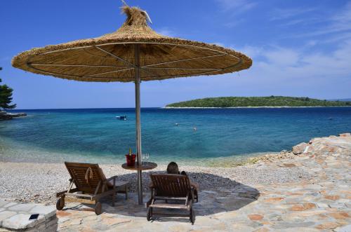 a person sitting in chairs under an umbrella on a beach at Guesthouse Gradina in Lovište