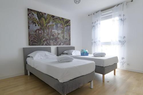 une chambre avec deux lits et un tableau au mur dans l'établissement Grand T2 neuf 2023 avec parking - 5 min du métro, à Créteil
