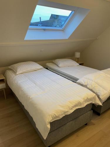 two beds in a room with a window at Pand 43 in Diksmuide