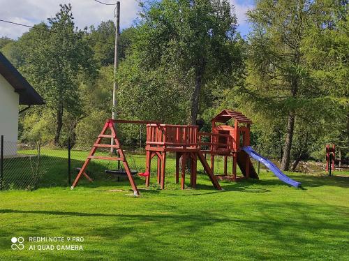 a playground in a yard with a slide and a ladder at Domki nad rzeką Solinką in Terka