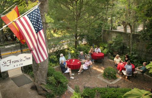a group of people sitting at tables in a garden with an american flag at St. Francis Inn - Saint Augustine in Saint Augustine