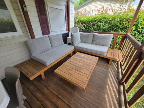 une terrasse couverte avec un canapé et des tables. dans l'établissement Grands mobil-homes 4 chambres clim-parking privées-possibilité d'accueil jusqu'à 20 voyageurs-Siblu, à Gastes