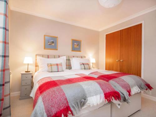 a bedroom with a bed with a red and gray blanket at Strathy in Dornoch