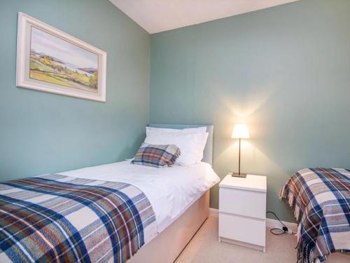 a small bedroom with two beds and a lamp at Strathy in Dornoch