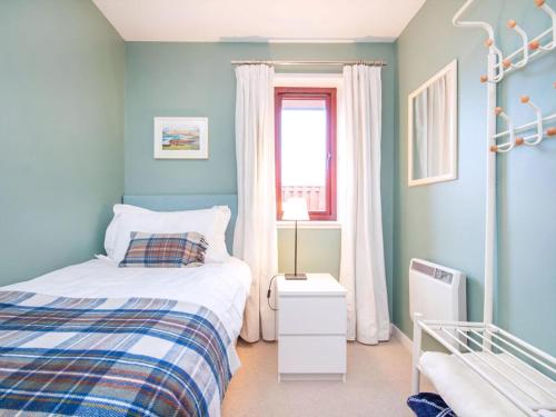 a blue bedroom with a bed and a window at Strathy in Dornoch