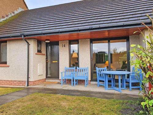 a house with blue chairs and a table on a patio at Strathy in Dornoch