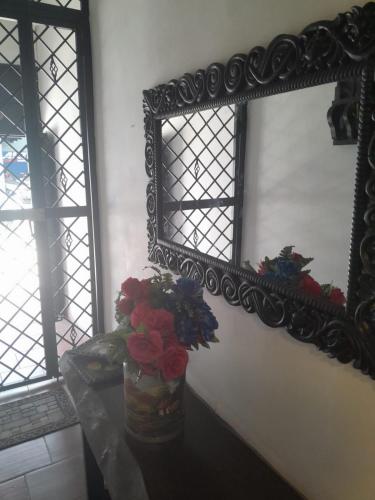 a mirror and a vase with flowers on a table at Hotel Boutique Casa Antigua in San Vicente de Chucurí