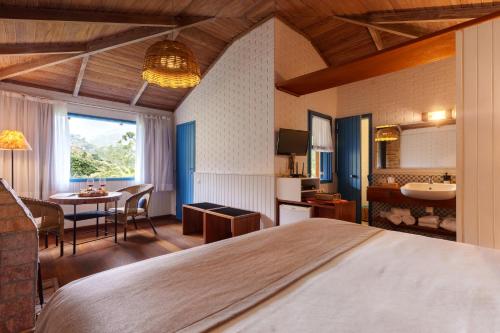 a hotel room with a large bed and a table at Parador Lumiar Boutique Hotel & Spa in Lumiar