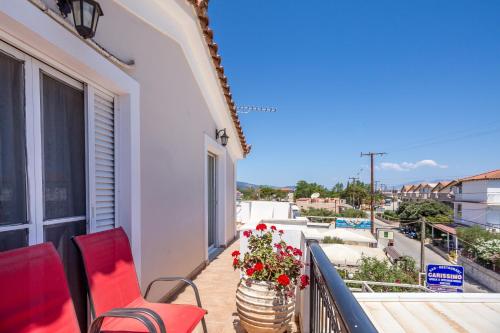 a balcony with two red chairs and flowers on it at Thetis in Alikanas