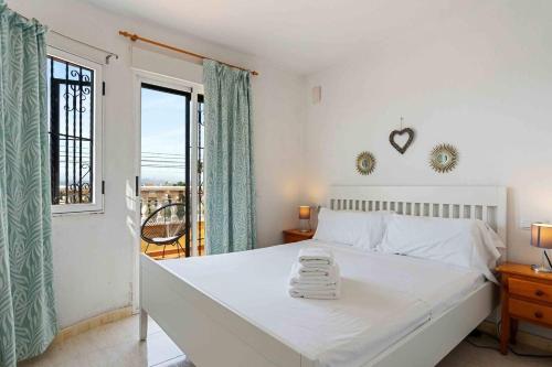 a bedroom with a large white bed with a window at Encantadora casa vacacional en El Chaparral in Torrevieja
