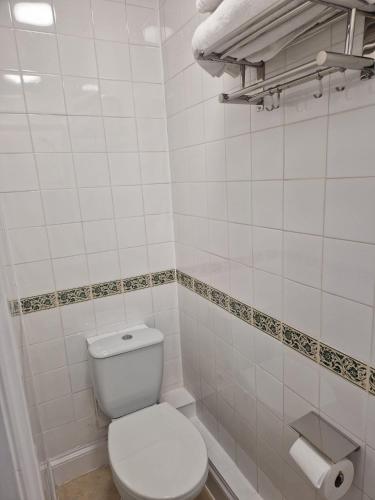 a white bathroom with a toilet and a toilet paper roll at The Swan Hotel Oxford in Eynsham