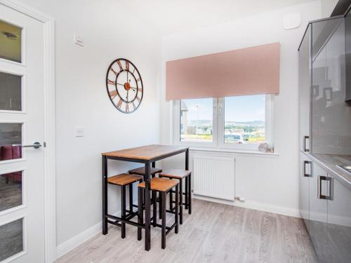 InshesにあるKessock View Apartmentのキッチン(テーブル、スツール、壁掛け時計付)