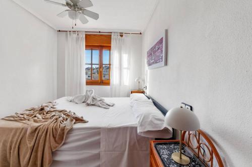 a white bedroom with a bed and a window at Acogedor bungalow de primera planta en Torreblanca in Torrevieja