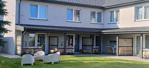a house with white furniture in a yard at Apartamenty Nadmorskie lofty in Gąski
