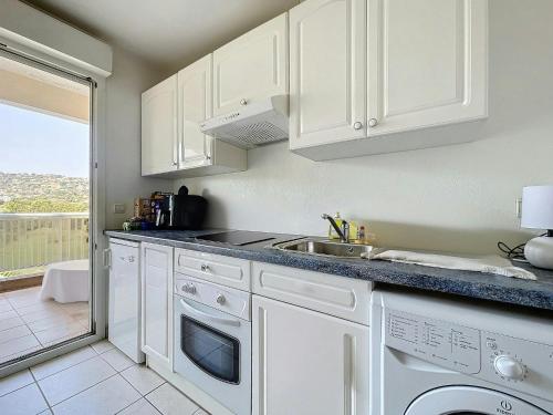 une cuisine avec des armoires blanches et un évier dans l'établissement Desirade-Piscine-Proche plage, au Golfe-Juan