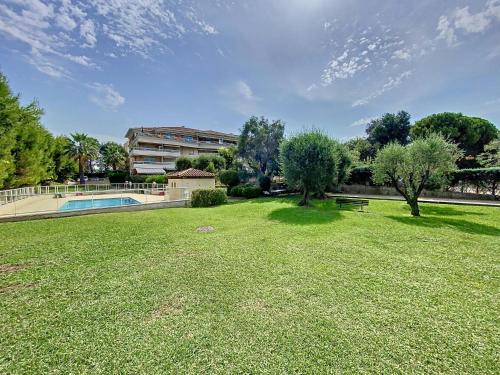 un parc avec une piscine, des arbres et un bâtiment dans l'établissement Desirade-Piscine-Proche plage, au Golfe-Juan