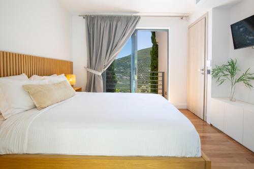 a bedroom with a white bed and a large window at The Dynasty Villas in Sivota