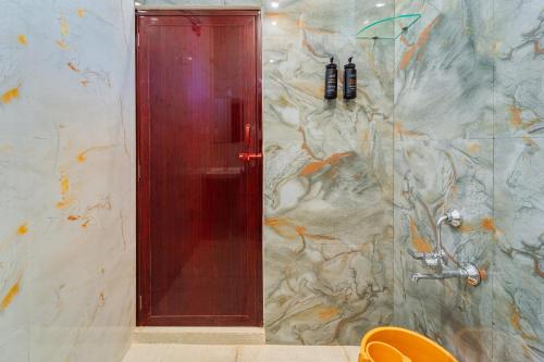 a shower with a red door in a bathroom at Neithal Farm Resort with Swimming Pool by Roscotel in Puducherry