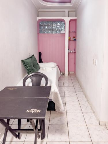 a room with a bed and a table and a window at Casa Araçás in Vila Velha