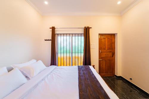 a bedroom with a bed with a window and a door at Neithal Farm Resort with Swimming Pool by Roscotel in Puducherry