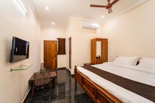 a bedroom with a bed and a flat screen tv at Neithal Farm Resort with Swimming Pool by Roscotel in Puducherry