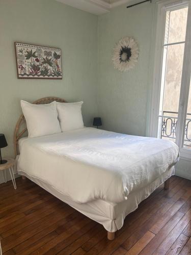 une chambre avec un grand lit avec des draps blancs dans l'établissement Appartement Paris Centre village Saint Martin, à Paris
