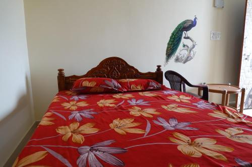 a bedroom with a bed with a red floral bedspread at Sivan Paadham Nilayam Guest House in Tiruvannāmalai