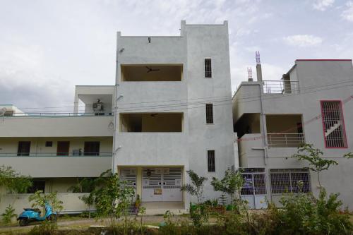 a tall white building with its doors open at Sivan Paadham Nilayam Guest House in Tiruvannāmalai