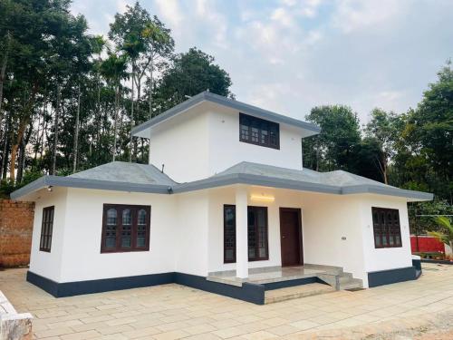 a white house with trees in the background at The Soul 1 Service Villa in Mananthavady