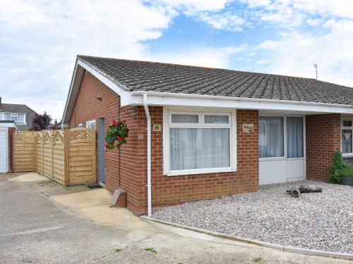 a red brick house with a fence and a driveway at Driftwood in Godshill