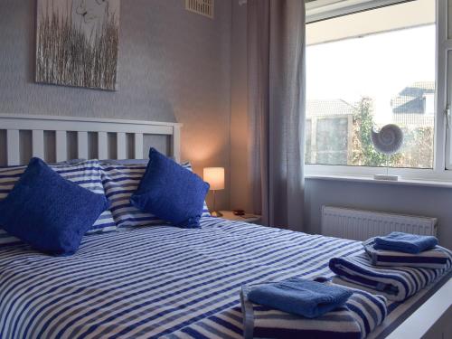 a bedroom with a bed with blue pillows and a window at Driftwood in Godshill