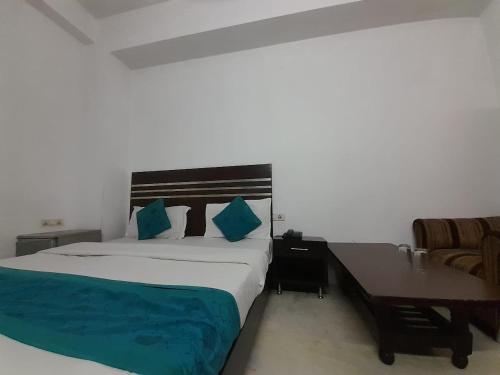 a bedroom with a large bed and a desk and a chair at Hotel Mandakini in New Delhi