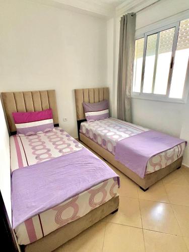 two beds sitting next to each other in a bedroom at Appartement À Martil in Martil