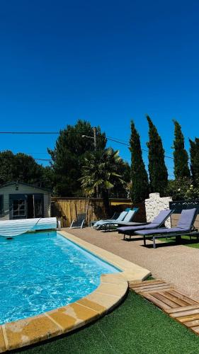 a swimming pool with two lounge chairs next to a house at La Régence Ch 2 in Brette-les-Pins