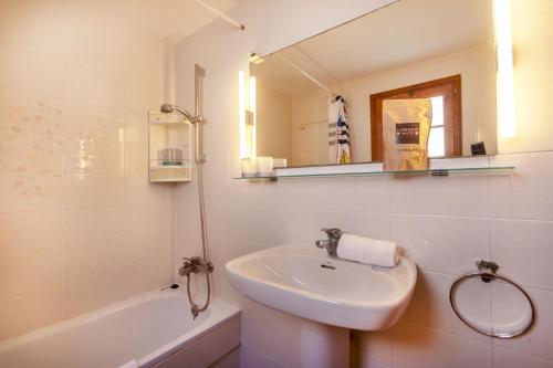 un bagno bianco con lavandino e specchio di La Paloma a Palafrugell
