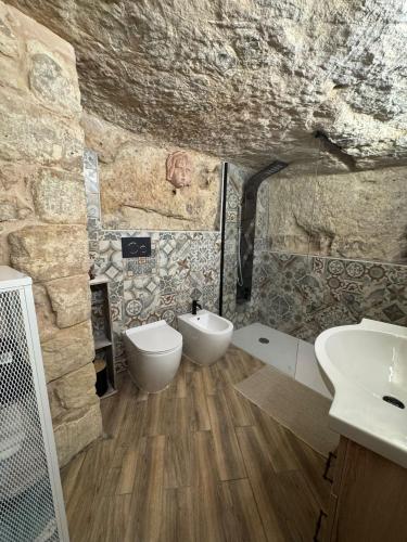 a stone bathroom with a sink and a toilet at La grotta Mutycense in Modica