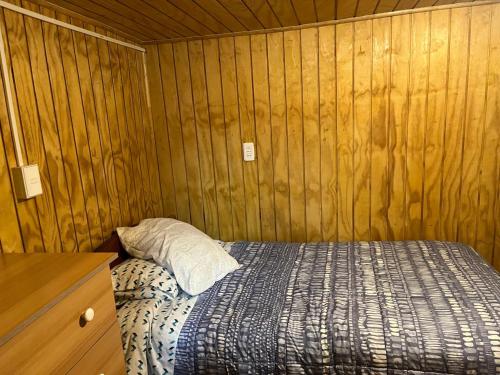 a bedroom with a bed and a wooden wall at Habitación cómoda por día in Valdivia