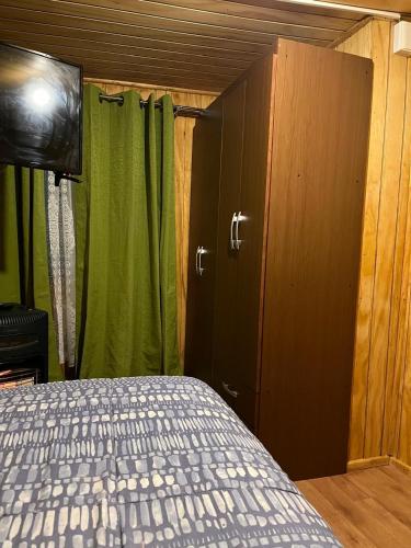 a bedroom with a bed and a green curtain at Habitación cómoda por día in Valdivia