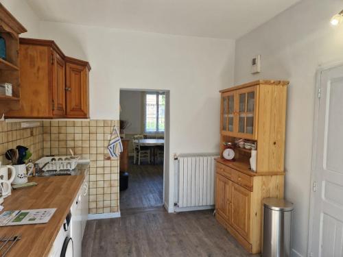 a kitchen with wooden cabinets and a table at Le Repos de Merlin in Paimpont