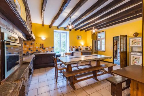 a large kitchen with a wooden table and chairs at Moulin de la Touche - Manoir Piscine Nature in Plouguenast Langast
