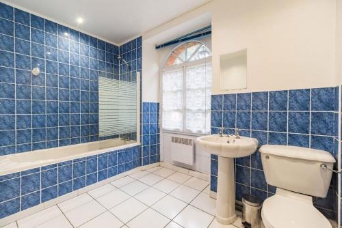 a blue tiled bathroom with a toilet and a sink at Moulin de la Touche - Domaine Piscine in Plouguenast Langast