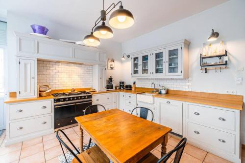 une cuisine avec des armoires blanches et une table en bois dans l'établissement Villa Au Beau Site Jardin, Cheminée & Mer proche, à Merlimont