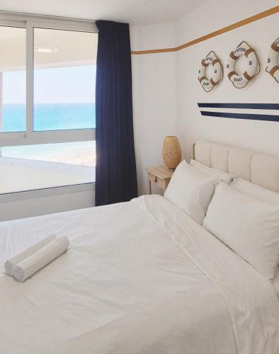 a bedroom with a white bed with a view of the ocean at GO to apartments in Leonardo in Bat Yam